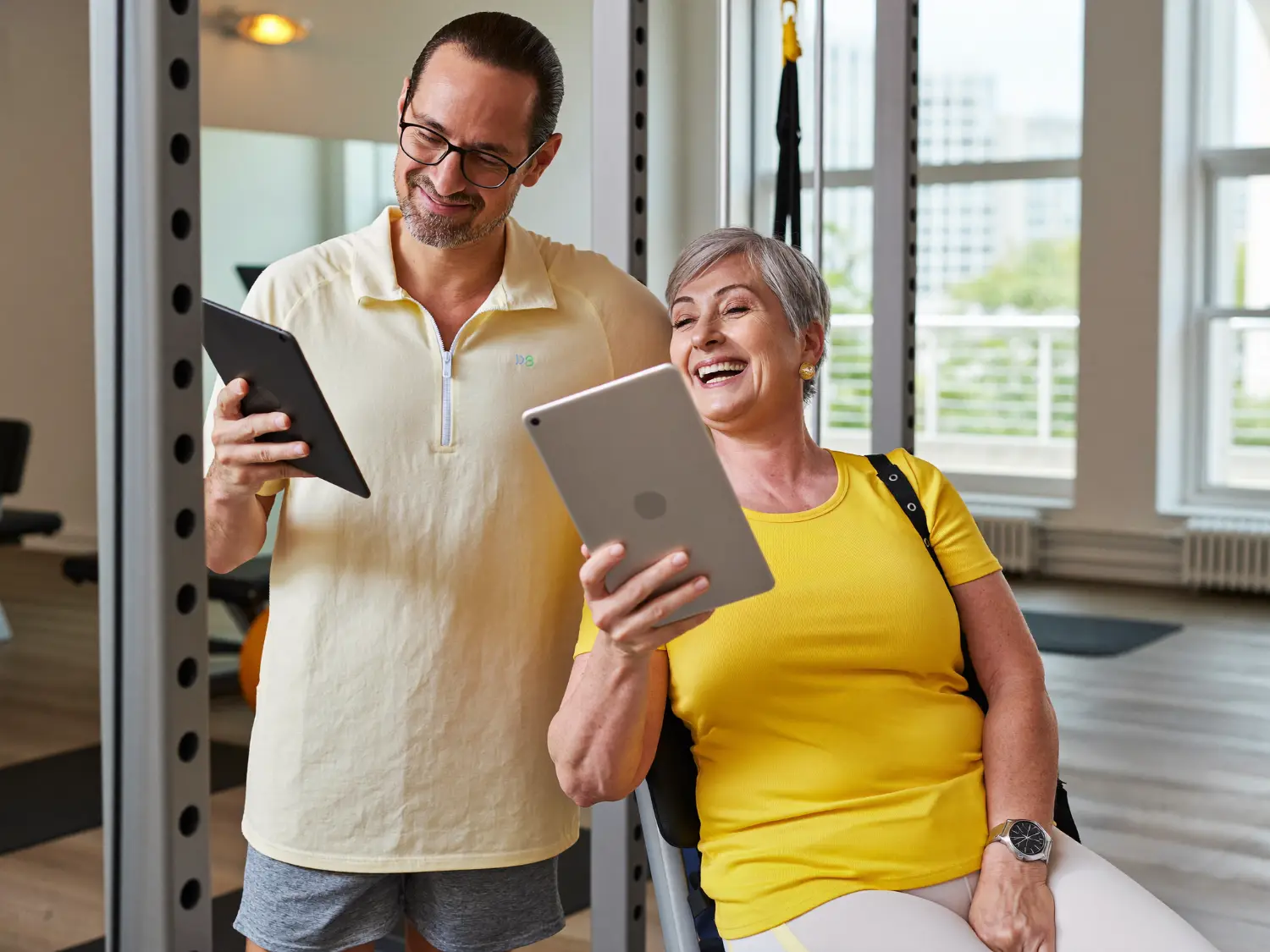 Older couple reviewing their training program on tablets at the gym