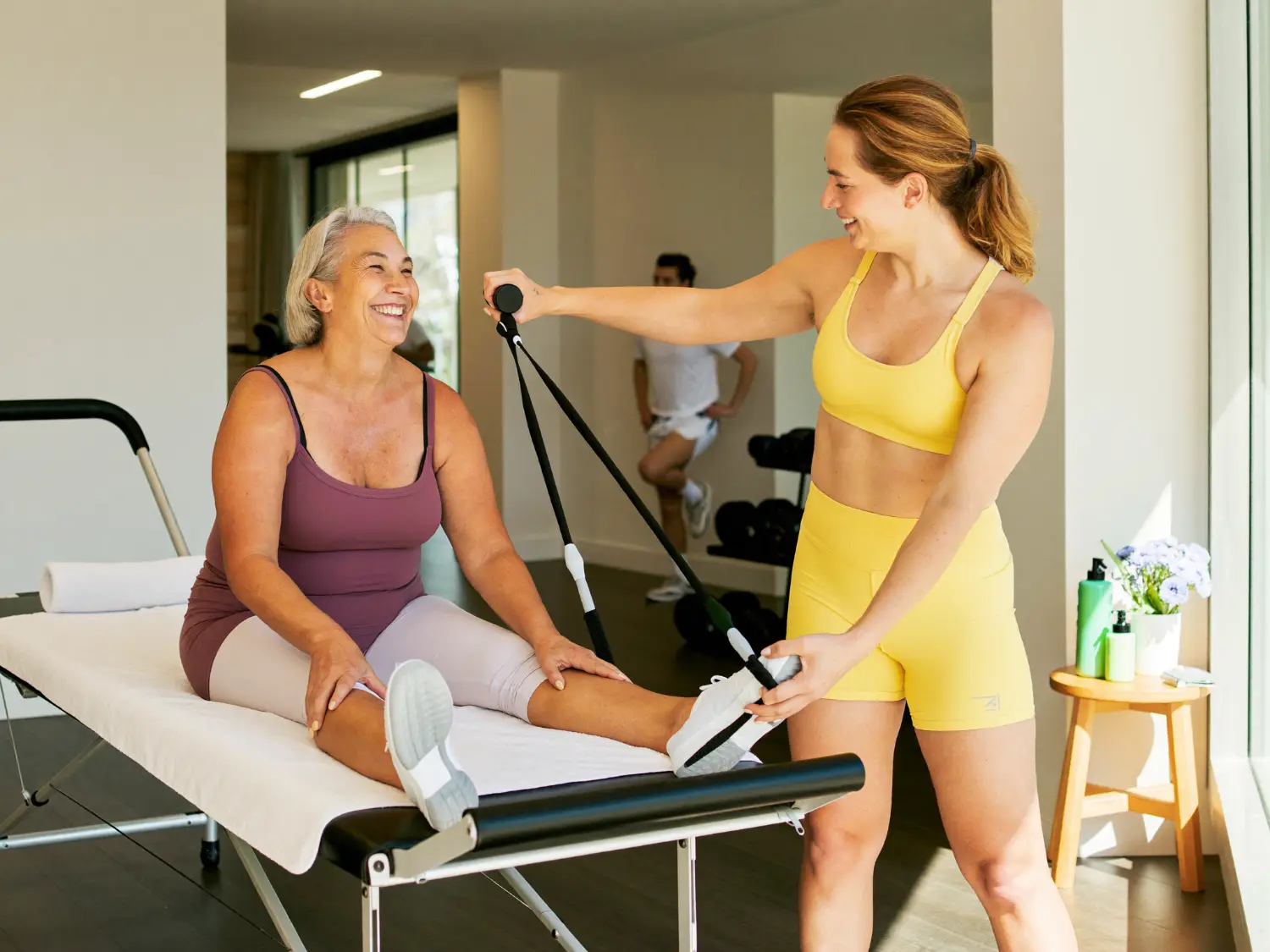 Trainer guiding an older woman through a cable exercise at the gym